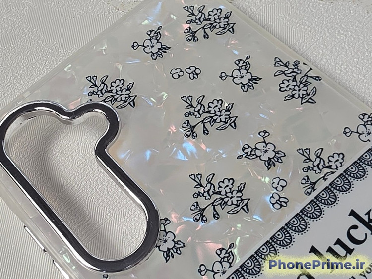 قاب گوشی سامسونگ S23 FE طرح گلهای ظریف مشکی روی بستر صدفی هولوگرافیک با نوشته Good Lucky و حلقه فلزی دوربین